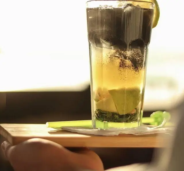 نوشیدنی خنک و لایه ای کافه رستوران رولینجا با ترکیب رنگی جذاب از لیمو، نعنا، یخ و پودر قهوه یا چای روی سینی چوبی.