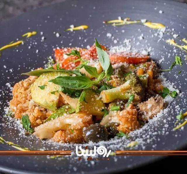 غذای سالم و لذیذ کافه رستوران رولینجا: پاستا یا کوسکوس با سبزیجات تازه (بروکلی، گل کلم، کدو، گوجه) و پنیر، با تزیین سس زرد و ریحان.