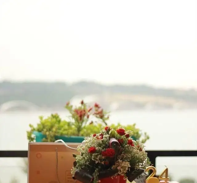 کافه رستوران رولینجا: میز آرایی جشن با گل‌های چشم‌نواز و شمع ۲۴، همراه با منظره آرامش‌بخش دریا و افق وسیع.
