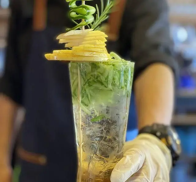 نوشیدنی خنک و سالم کافه رستوران رولینجا: کوکتل میوه و سبزیجات با تزیین خیار و سیب تازه، سرو توسط پرسنل حرفه‌ای.