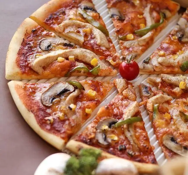 پیتزا لذیذ و تازه کافه رستوران رولینجا، با ترکیبات عالی قارچ، فلفل دلمه‌ای، ذرت و تکه‌های مرغ، مناسب برای تجربه‌ای به یادماندنی.