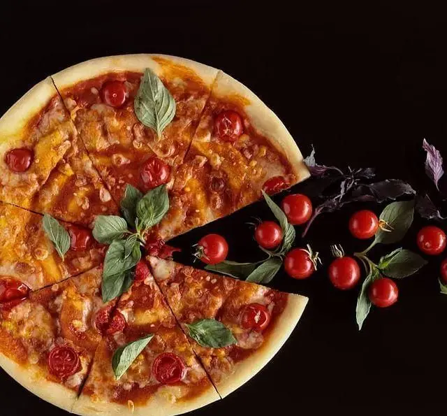 پیتزا خوشمزه و زیبای کافه رستوران رولینجا با سس گوجه، پنیر، گوجه گیلاسی و ریحان تازه، آماده سرو. لذت یک پیتزای ایتالیایی اصیل را تجربه کنید.