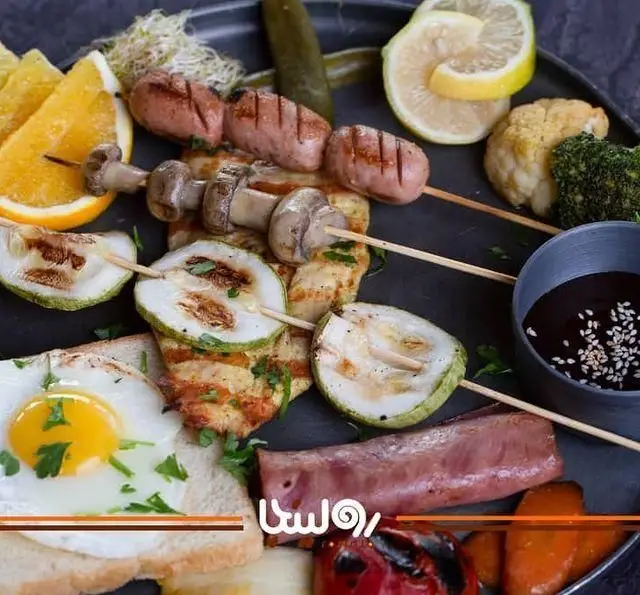 پلیت صبحانه گریل کافه رستوران رولینجا: سوسیس، مرغ، قارچ، کدو کبابی، تخم مرغ، پرتقال و سبزیجات تازه. انتخابی سالم و خوشمزه.