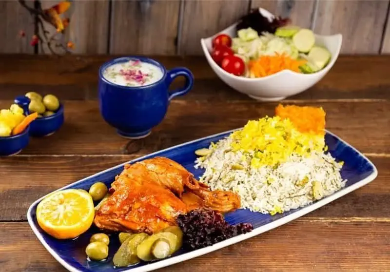 غذای انصار: سبزی پلو با مرغ زعفرانی و زرشک، همراه دوغ محلی، سالاد تازه، زیتون و ترشی. لذت غذای سنتی و باکیفیت ایرانی را تجربه کنید.