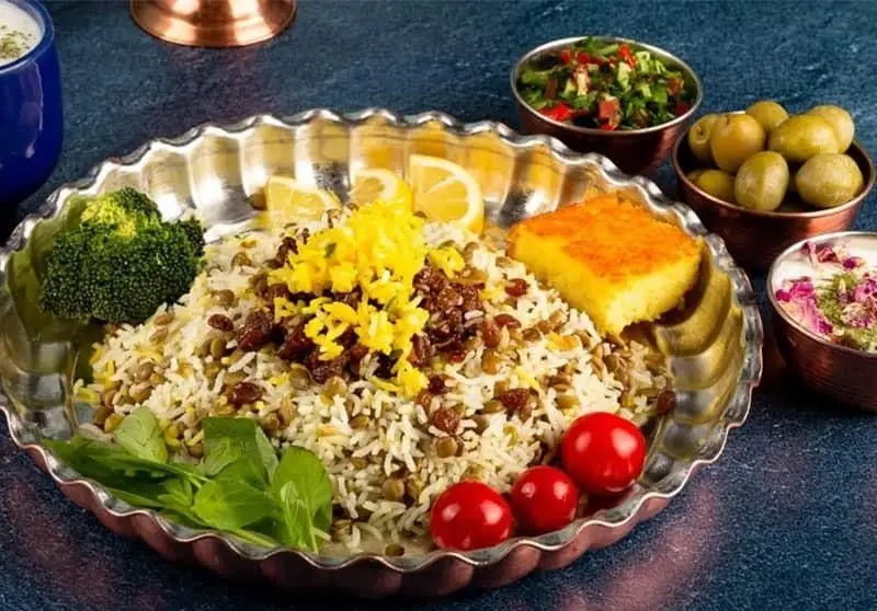 یک بشقاب عدس پلو مجلسی و خوش‌رنگ با ته دیگ زعفرانی، همراه با مخلفات متنوع از بهترین غذای انصار. سفارش آنلاین غذای ایرانی.