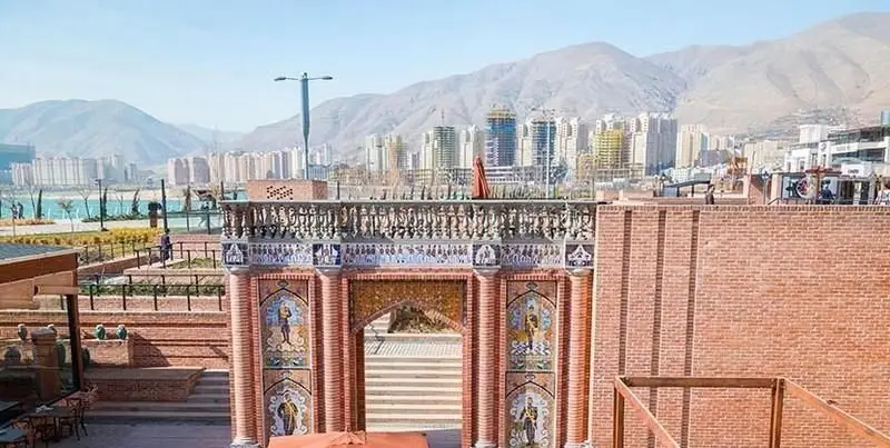 نمایی دلنشین از رستوران ایرانی دروازه طهرون با معماری سنتی ایرانی و منظره وسیع دریاچه چیتگر و تهران.