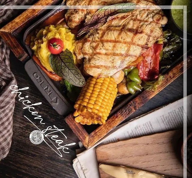 چیکن استیک کبابی لذیذ و تازه رستوران دالاترا با دورچین متنوع شامل پوره سیب زمینی، ذرت و فلفل های رنگی.