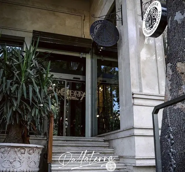 نمای بیرونی لوکس و ورودی مجلل رستوران و کافه دالاترا در تهران، با پله‌های سنگی، گیاهان زینتی و تابلوهای زیبا.