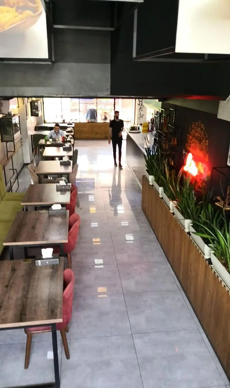 فضای داخلی مدرن فست فود لیرو با میز و صندلی‌های چوبی، دکوراسیون جذاب، گیاهان تزئینی و نورپردازی دلنشین برای مشتریان.