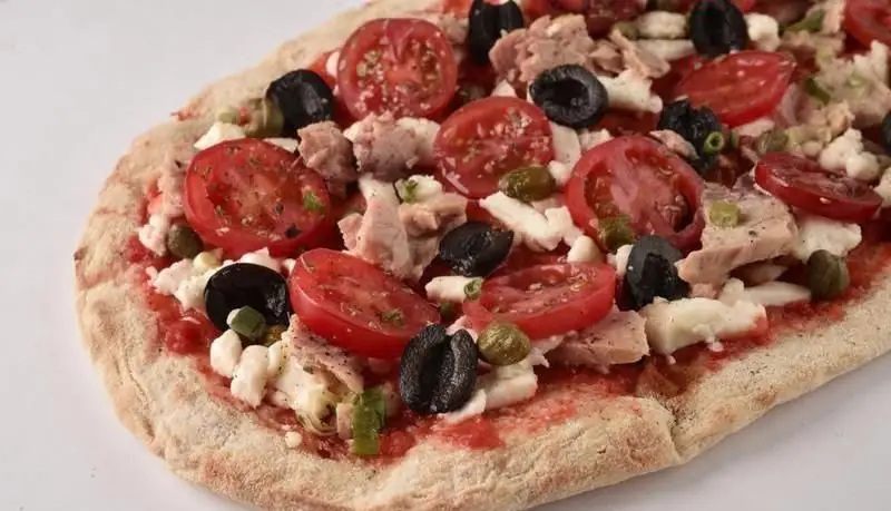 پیتزای خوشمزه و سالم پیتزایی استریت آرت با گوجه فرنگی تازه، زیتون سیاه، تکه‌های ماهی تن، پنیر فتا و کاپر. انتخابی عالی برای دوستداران طعم مدیترانه‌ای.