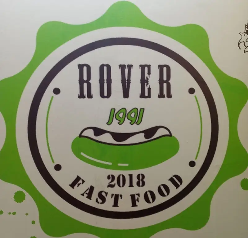 لوگوی فست‌فود ROVER با طرح دایره‌ای، شامل نام ROVER، سال 1991، هات‌داگ سبز با سس، و متن FAST FOOD 2018 روی پس‌زمینه سبز و سفید.