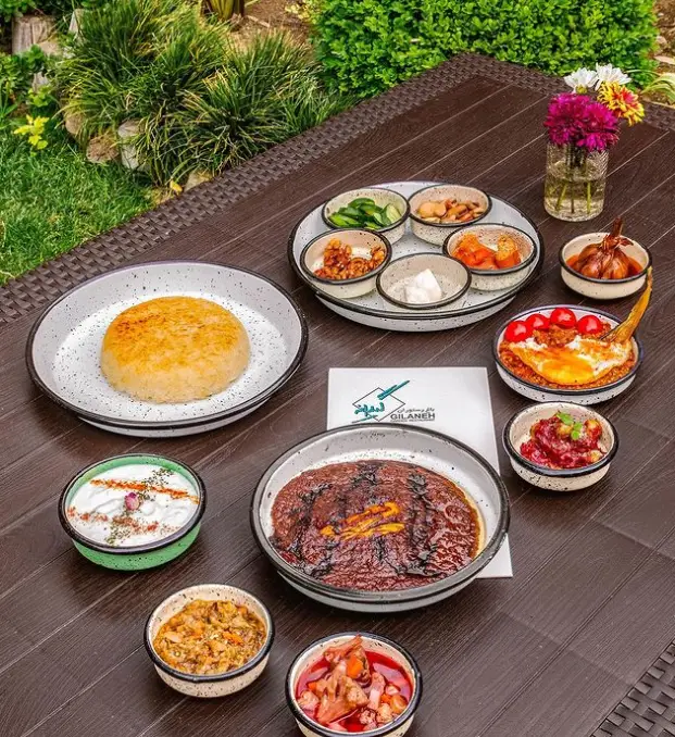 تجربه طعم اصیل غذای گیلانی در رستوران گیلانه: خورش فسنجان، میرزاقاسمی، برنج کته، ماست و انواع مزه‌های محلی در فضایی سرسبز.