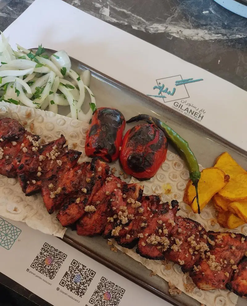 کباب لذیذ و خوشمزه از رستوران باغ گیلانه، شامل گوشت کبابی با دورچین پیاز، فلفل و چیپس. بهترین غذای ایرانی در محیطی دلنشین.