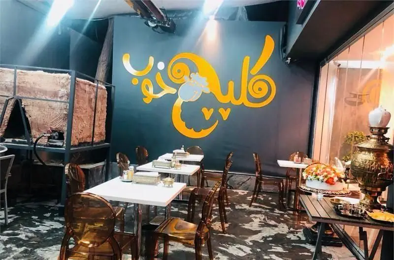 فضای داخلی رستوران سان لیو با دکوراسیون مدرن و شیک، میز و صندلی‌های شفاف، دیوارنگاری هنری فارسی و سماور سنتی زیبا.