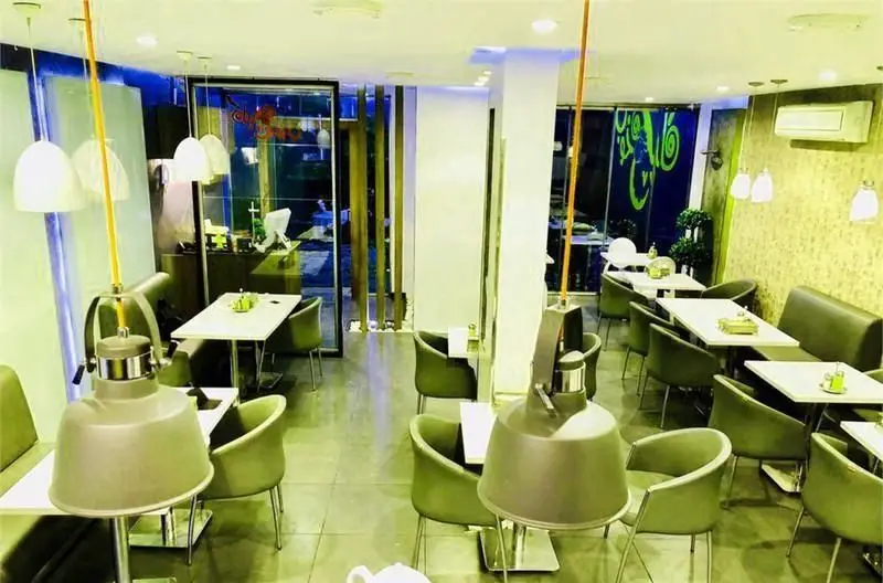 تصویری از فضای داخلی رستوران و کافه سان لیو با دکوراسیون مدرن، میز و صندلی‌های راحت و شیک به رنگ سبز، نورپردازی خاص و محیطی دلنشین برای پذیرایی.