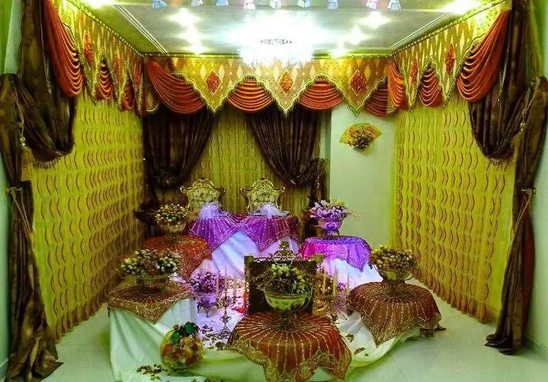 فضای داخلی مجلل تالار قصر گوهر با دکوراسیون سنتی و پرده‌های شیک، میزهای تزئین شده و گل‌آرایی برای مراسم عروسی و عقد.