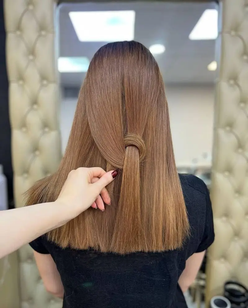 مدل موی صاف و ابریشمی به رنگ قهوهای روشن با یک گره ساده و شیک در پشت سر، خدمات حرفهای آرایش مو در سالن زیبایی آرلا