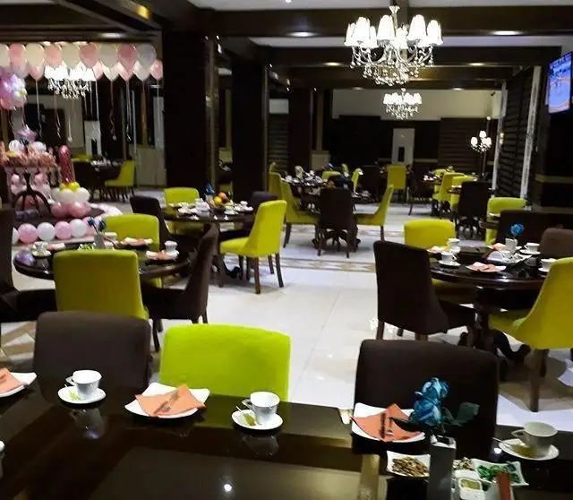 فضای داخلی جذاب کافه رستوران مانیا با دکوراسیون مدرن، میز و صندلی های شیک، و آماده سازی برای جشن تولد و میهمانی.