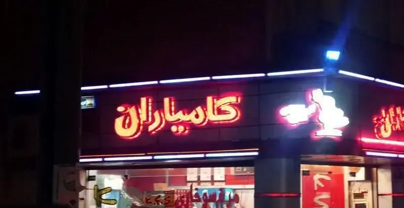 تصویری از تابلوی نئونی پرنور فست فود KFS کامیاران در شب، نمایش دهنده نام و برند محبوب فست فود در شهر.