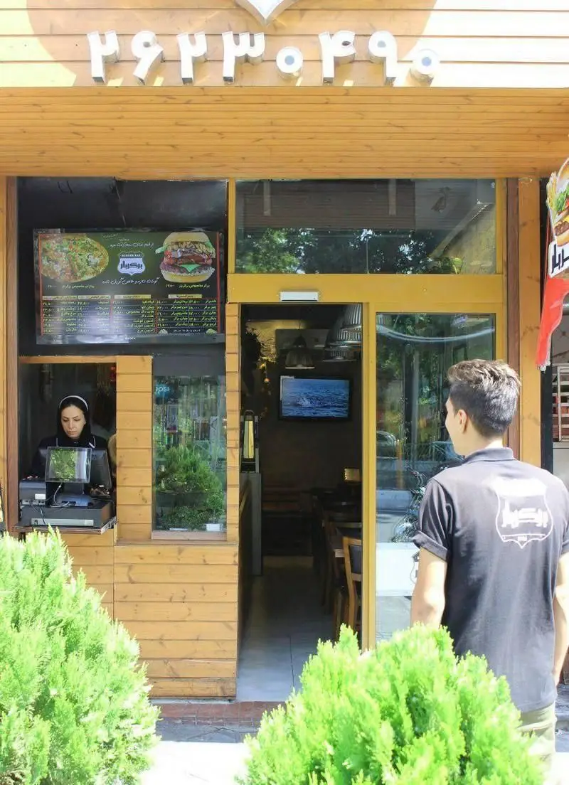 ورودی و نمای خارجی رستوران فست فود برگر بار با منوی متنوع همبرگر و پیتزا، حضور صندوقدار و مشتری. تلفن ۲۶۲۳۰۳۹۰