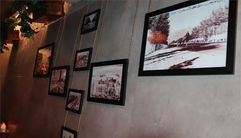 فضای داخلی گرم برگر بار با دکوراسیون دیواری منحصربه‌فرد، شامل قاب عکس‌های کلاسیک و هنری، ایده‌آل برای تجربه یک برگر عالی.