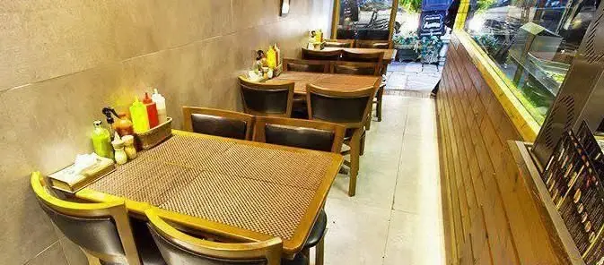 فضای داخلی شیک و دنج برگر بار با میز و صندلی‌های چوبی حصیری، آماده پذیرایی از مشتریان در محیطی گرم و دوستانه.