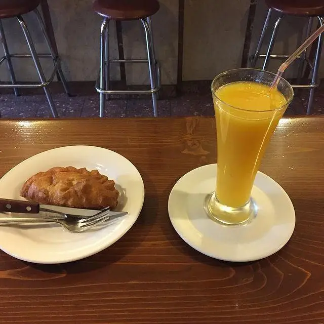 شیرینی طلایی و آب پرتقال تازه و گوارا در کافه لینت. لذت یک صبحانه یا میان وعده دلپذیر بر روی میز چوبی کافه.