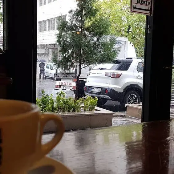 فضای داخلی کافه لینت در یک روز بارانی، با فنجان قهوه روی میز و منظره دلنشین بیرون، محیطی دنج و آرام برای گذراندن وقت.