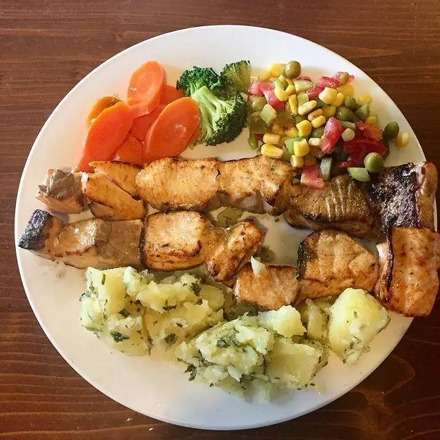 غذای خوشمزه و سالم کافه لینت: ماهی گریل، سیب‌زمینی پخته، هویج، بروکلی و سالاد سبزیجات تازه. مناسب برای یک وعده کامل و رژیمی.