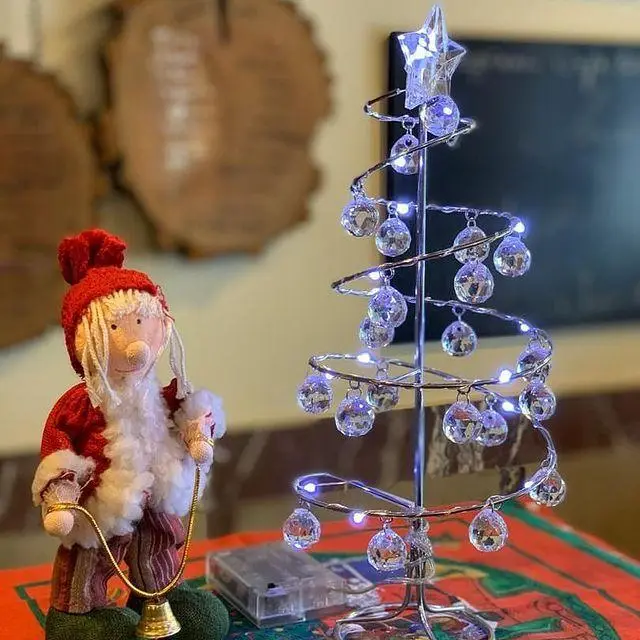 دکوراسیون زیبای کریسمس کافه لینت شامل درخت کریستال LED روشن و مجسمه بابانوئل با زنگوله طلایی. فضایی دلنشین برای زمستان.