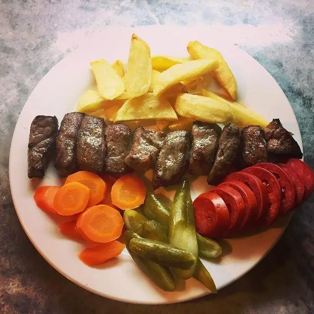 بشقاب کامل کباب کوبیده کافه لینت: گوشت لذیذ، سیب‌زمینی سرخ‌کرده، هویج، خیارشور و برش‌های تازه گوجه.