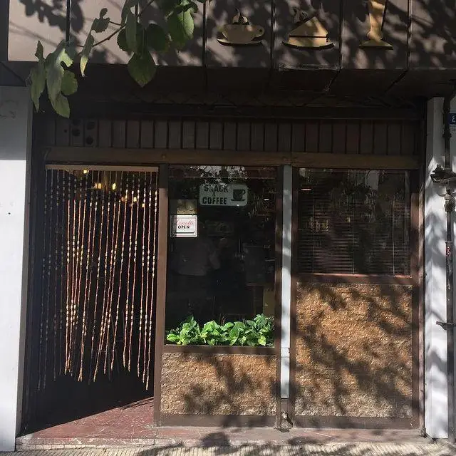 نمای بیرونی کافه لینت با ورودی دنج و تابلوی SNACK COFFEE، همراه با نمادهای قهوه و دکوراسیون چوبی گرم. مکانی عالی برای تجربه قهوه در کافه لینت.