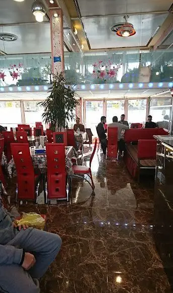 فضای داخلی رستوران موسوی با میز و صندلی‌های قرمز، مشتریان در محیطی دنج. دکوراسیون شیک و مدرن، مکانی ایده‌آل برای دورهمی‌های خانوادگی و دوستانه.