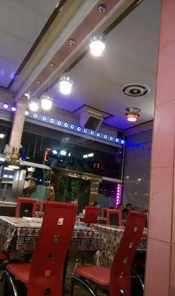 تصویری از دکوراسیون داخلی رستوران موسوی: صندلی‌های قرمز، میزهای با رومیزی طرح‌دار، نورپردازی سقفی، و ال‌ای‌دی‌های آبی برای فضایی دلنشین.