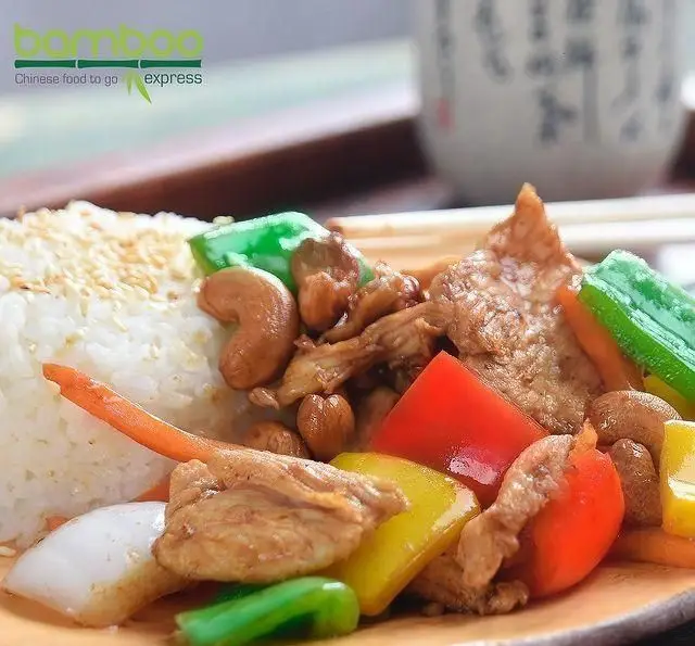 غذای چینی رستوران بامبو اکسپرس: بشقاب برنج با کنجد، مرغ، بادام هندی و سبزیجات تازه شامل فلفل دلمه ای رنگی و هویج. آماده بیرون بر