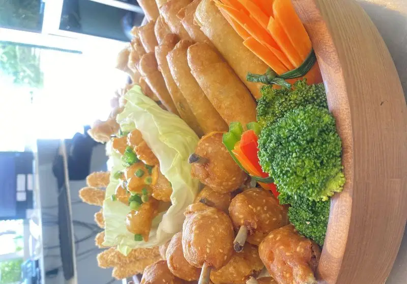 سینی فینگرفود متنوع و اشتهاآور رستوران بامبو اکسپرس، با رول بهاری، مرغ کنجدی، کاهو، بروکلی و هویج تزئینی.
