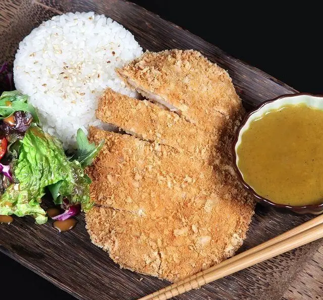 کاتسو کاری مرغ ترد با برنج بخارپز، سالاد تازه و سس کاری مخصوص رستوران بامبو اکسپرس. یک غذای آسیایی لذیذ و کامل.