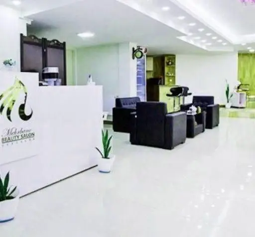 طراحی دکوراسیون داخلی مدرن و شیک سالن زیبایی با مبلمان مشکی، کانتر پذیرش سفید و گیاهان تزیینی در محیطی روشن و باز