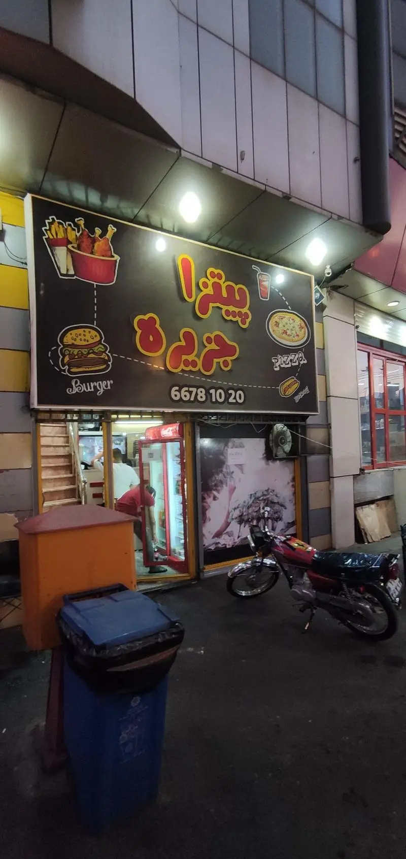 فست فود جزیره: تابلوی روشن رستوران با تصاویر پیتزا، برگر، مرغ سوخاری، سیب زمینی و هات داگ به همراه شماره تماس 66781020.