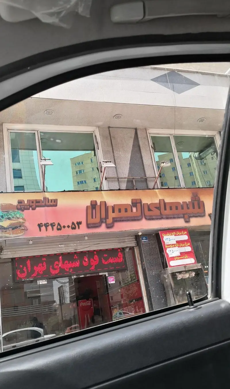 تصویری از نمای خارجی فست فود شبهای تهران، ارائه‌دهنده ساندویچ، پیتزا و مرغ بریان، با شماره تلفن ۴۴۶۵۰۰۵۳ و لوگوی کوکاکولا