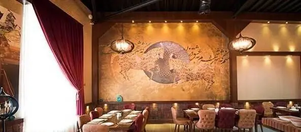 فضای دلنشین و مجلل کافی شاپ شاندیز اعیانی، با دیوارنگاره چشم‌نواز با خط نستعلیق و طراحی اسلیمی، محیطی ایده‌آل برای صرف غذا و قهوه.