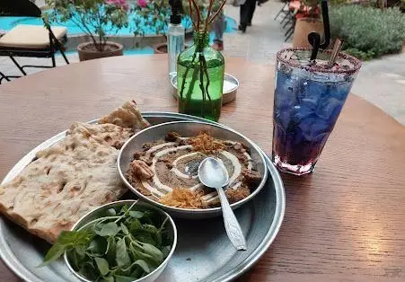 صبحانه حلیم لذیذ کافه روحی در محوطه زیبای باغ نگارستان با نان داغ، سبزی تازه و نوشیدنی خنک در محیطی دلنشین.