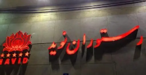 تابلوی نئونی رستوران ایرانی نوید با نور قرمز در شب، نشان‌دهنده ورودی یک رستوران لوکس و با کیفیت ایرانی با 5 ستاره.