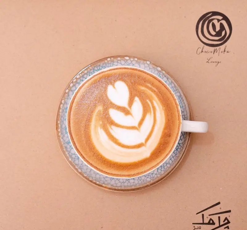 یک فنجان قهوه لاته آرت هنرمندانه با طرح برگ و قلب در کافه رستوران چک مک لانژ. لحظاتی دلپذیر با نوشیدنی خاص.