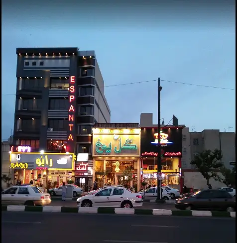 تصویری جذاب از کافی شاپ گل یخ در شب، با نورپردازی زیبا در خیابان پرجنب و جوش شهری، مکانی دلپذیر برای مشتریان.