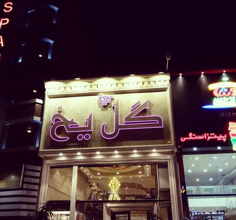 نمای شبانه کافی شاپ گل یخ با تابلوی نئونی بنفش و لوگوی خاص، انعکاس دکوراسیون داخلی شیک و مدرن، مکانی ایده‌آل برای دوستداران قهوه.