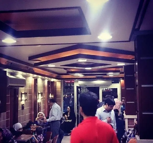 فضای داخلی کافی شاپ گل یخ با دکوراسیون مدرن، سقف نورپردازی شده و مشتریانی در حال لذت بردن از محیط گرم و دوستانه.