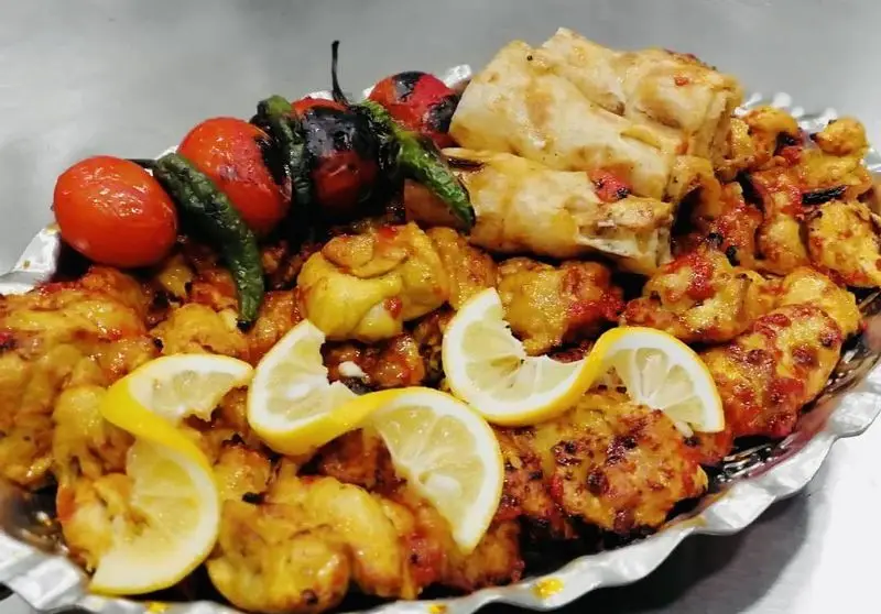 سینی بزرگ و دلپذیر جوجه کباب ویژه خانه کباب درین، با تکه های مرغ طعم دار، گوجه و فلفل کبابی، لیمو و نان محلی.