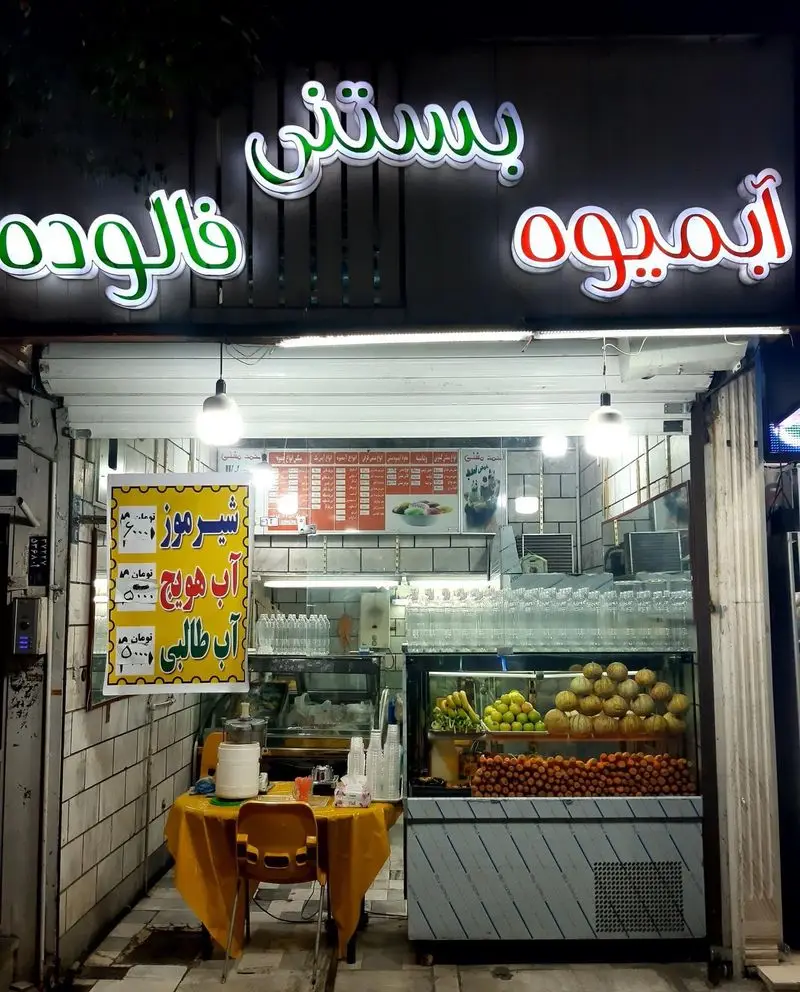 مغازه بستنی آبمیوه سید با تابلوهای روشن بستنی، فالوده و آبمیوه. نمایش میوه‌های تازه، شیرموز و آب هویج آماده.