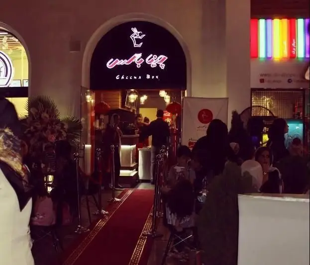 ورودی پر جنب و جوش رستوران "چینا باکس" در شب، با دکوراسیون شرقی و فرش قرمز، مکانی دلپذیر برای لذت بردن از غذاهای چینی با کیفیت بالا.